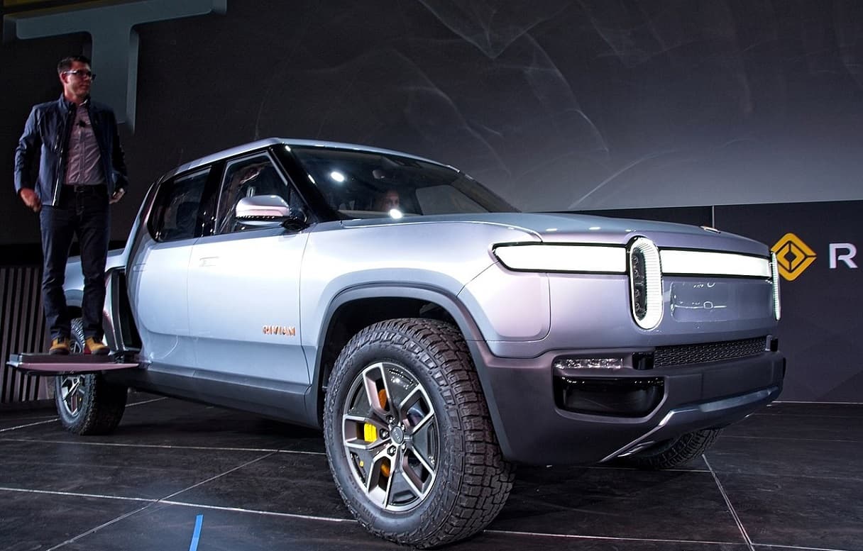1280px-Rivian_founder_and_CEO_Robert__RJ__Scaringe_at_the_debut_of_the_Rivian_R1T_pickup_at_the_2018_Los_Angeles_Auto_Show_November_27_2018-1